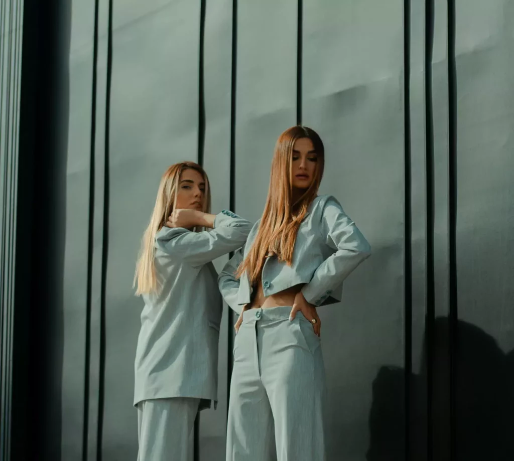 2 women in white long sleeve shirt standing beside glass window